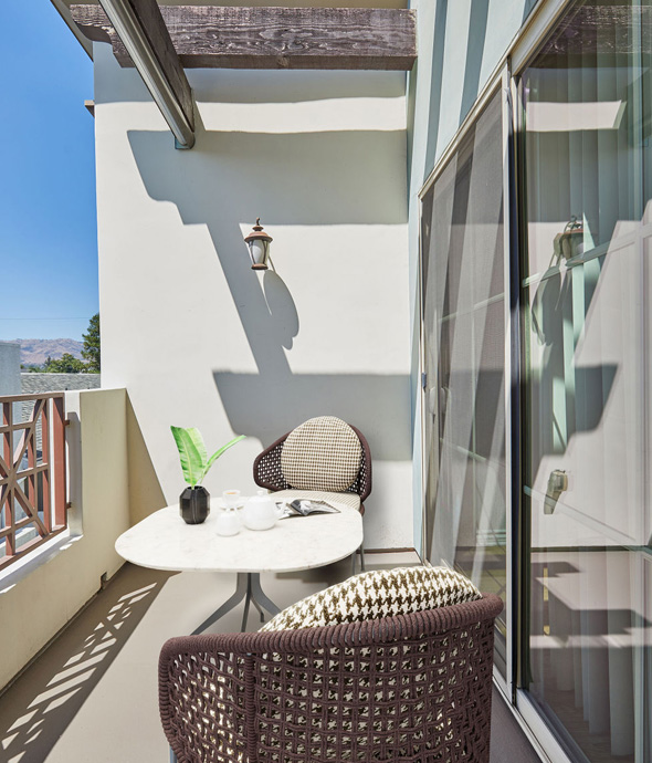 sun shining on out door unit patio area with modern updated woven basket chair and white table