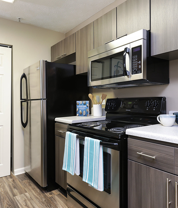 Kitchen with rich wood floors and cabinets, smooth white countertops, and stainless steel appliances.