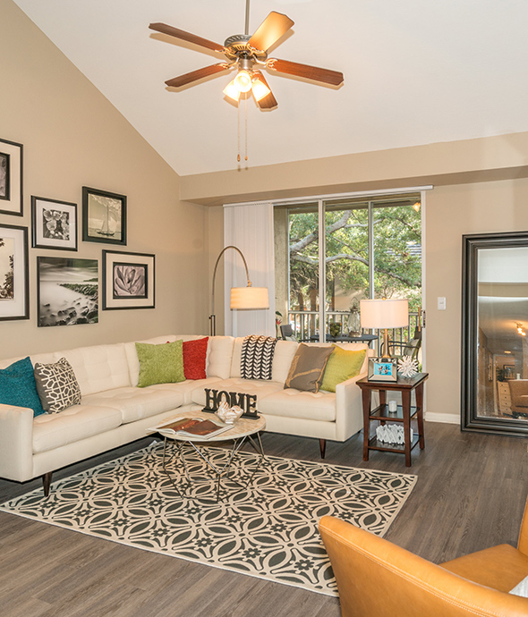 Living room with vaulted ceiling, large sectional couch, wood floor with rug, and large windows.
