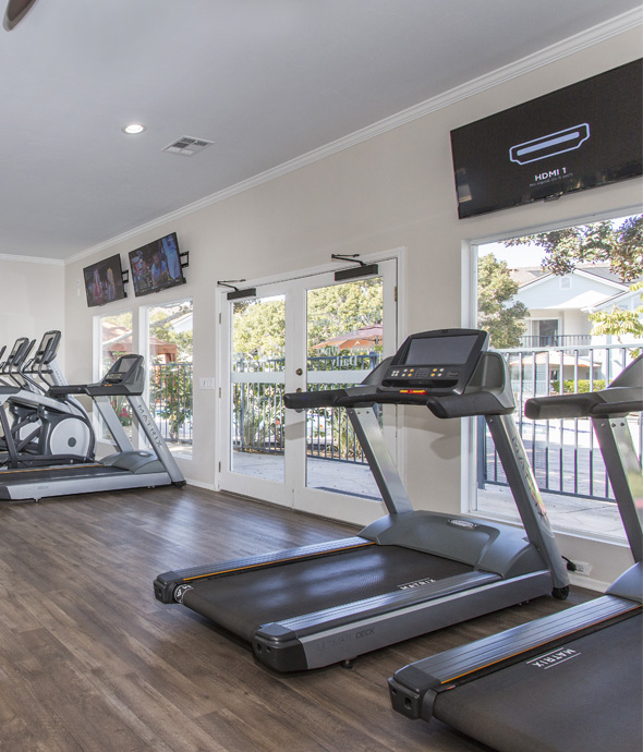 fitness center with hardwood floors and updated workout bikes, treadmills aligned along the wall